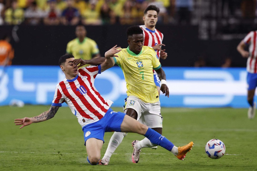 El delantero brasileño Vinícius Júnior (c) fue registrado este viernes, 28 de junio, al disputar un balón con el centrocampista paraguayo Miguel Almirón (i), durante un partido del grupo D de la Copa América 2024, en el estadio Allegiant de Las Vegas (Nevada, EE.UU.) EFE/Caroline Brehman