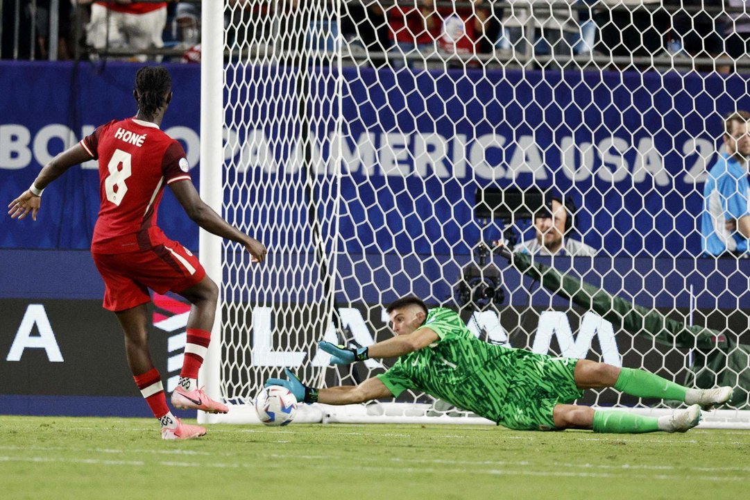 El guardameta de la selección uruguaya de fútbol, Sergio Rochet (d), fue registrado este sábado, 13 de julio, al detenerle un cobro de tiro penal al canadiense Ismael Koné, durante la definición del partido por el tercer puesto de la Copa América 2024, en el estadio Bank of America de Charlotte (Carolina del Norte, EE.UU.). EFE/Erik S. Lesser